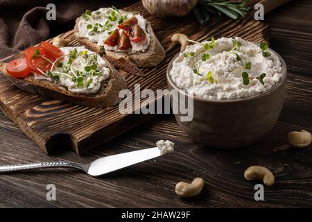 Frischkäse aus fermentierten Cashewkernen auf dunklem Holzhintergrund, gesunde vegane Nahrung. Stockfoto