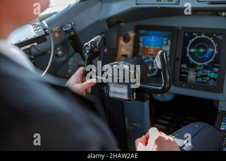 Männlicher Pilot sitzt vor dem Steuerrad im Cockpit des Flugzeugs Stockfoto