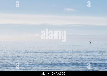 Ein Paddelboarder paddelt am späten Nachmittag in Hunstanton, Norfolk, Großbritannien, in der Nähe eines flachen Meeres entlang der Küste. November 2021 Stockfoto