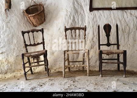 Drei Stühle mit Korb vor weißer Wand, verlassene Höhlenwohnung, verlassenes Haus, Verlorener Ort, Andalusien, Spanien Stockfoto