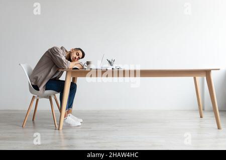 Erschöpfter Junger Mann Schläft Bei Der Arbeit Und Sitzt Am Schreibtisch Stockfoto