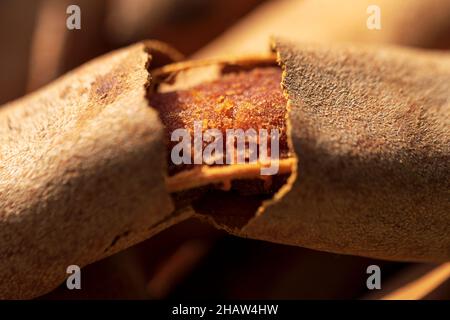 Makroaufnahme einer geschälten süßen und sauren Tamarindenfrucht. Braun reif gebrochen Tamarinde Hintergrund Textur Konzept. Stockfoto