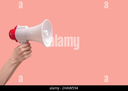 Megaphon in den Händen der Frau auf einem rosa Hintergrund. Speicherplatz kopieren. Stockfoto