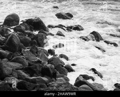 Monochrome, große schwarze Lavasteine in der Brandung am Strand von Rocha da Relva, Sao Miguel Island, Azoren, Portugal Stockfoto