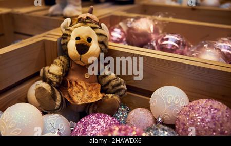 Neujahrsspielzeug. Fotofigur eines Teddybären unter Weihnachtskugeln in einem Supermarkt Stockfoto