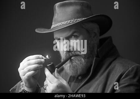 Bärtiger Mann, der traditionelle Pfeife raucht. Modisches Porträt. Stockfoto