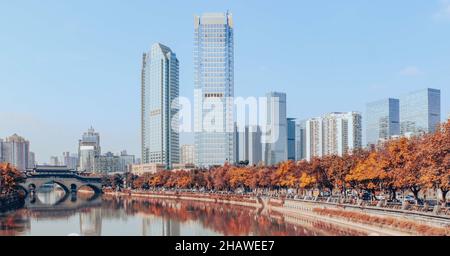 Herbstlandschaft in Chengdu, Herbstbäume säumen die Ufer des Jinjiang Flusses durch die Anshun Brücke mit modernen Gebäuden im Hintergrund, Chengdu ist ein Stockfoto