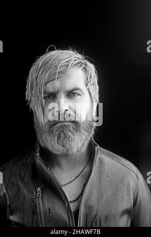 Portrait des brutalen jungen Mannes mit langen nassen blonden Haaren in Lederjacke. Männliche Mode, Beauty-Konzept. Klassischer Style. Studioaufnahme. Stockfoto