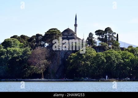 Ioannina, Griechenland - 27. Juni 2021: Menschen auf der Promenade entlang des Pamvotida Sees und der Aslan Pasha Moschee auf einem Hügel Stockfoto