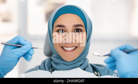 Kosmetische Zahnheilkunde. Lächelnde Islamische Dame In Hijab Posiert Während Des Checkup In Der Klinik Stockfoto