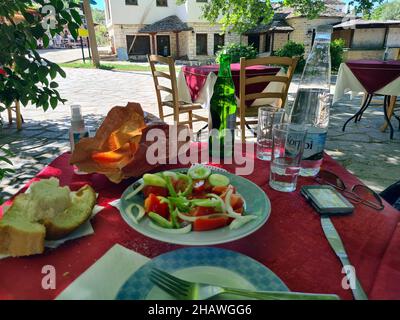Ioannina, Griechenland - 27. Juni 2021: Tisch mit Getränken und Salat im Gartenbereich eines Restaurants auf der winzigen Insel im Pamvotida-See Stockfoto