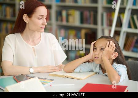 Trauriges Mädchen und junge Frau, die am Tisch studieren Stockfoto