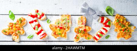 Weihnachtspizza für das Abendessen für Kinder, mit Ausstechformen, in Form von traditionellen Weihnachts-Symbolen - Candy Cane, Lebkuchenmann, Weihnachtsbaum, lustig f Stockfoto