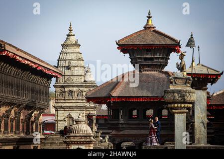 Bhaktapur, Bagmati, Nepal. 15th Dez 2021. Ein frisch vermädchenes Paar posiert für ein Foto nach der Hochzeit auf dem Bhaktapur Durbar Square. Das alte Palastgebiet, reich an antiker Architektur, zieht Tausende von einheimischen und ausländischen Touristen sowie Fotoliebhaber an, um die Fotos zu machen. Quelle: Amit Machamasi/ZUMA Wire/Alamy Live News Stockfoto