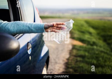 Der Fahrer wirft Plastikmüll vom Autofenster auf der Straße weg. Umweltschutz. Verantwortungslose Menschen und Plastikverschmutzung Stockfoto