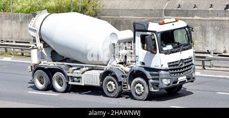 Seite & Vorderansicht Fahrer in weiß sauber unmarkiert Mercedes Lieferwagen LKW Chassis Kabine bereit Mischung Beton Zement Mischtrommel Fahren auf UK Autobahn Stockfoto