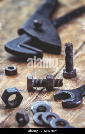 Vintage-Werkzeuge auf dem Tisch, selektiver Fokus auf Schrauben- und Mutternbefestigungen. Sanitär-Werkzeug und Industrieanlagen. Rostige Schraube Stockfoto