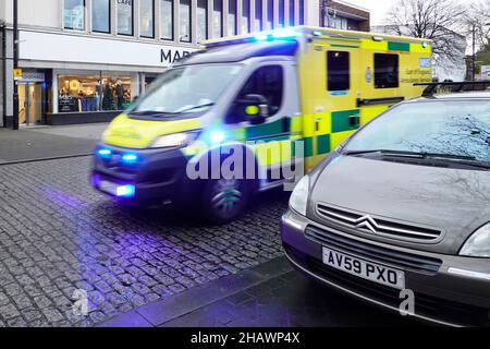 Motion Blur Vorder- und Seitenansicht East of England NHS Krankenwagen auf blauem Licht Notruf fahren auf Geschwindigkeit nass gepflasterten Straße Brentwood High Street UK Stockfoto