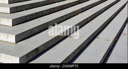 Nahaufnahme gerade Linie von breiten Steintreppen bei Sonnenschein Aufsteigen im Schatten auf Ecktreppen in der City of Londonmit herbstlichen Herbstauffällen verlässt England Großbritannien Stockfoto