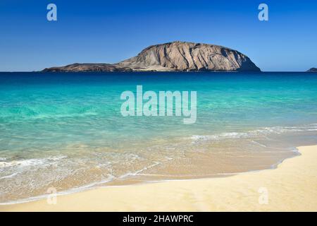 Schöne Playa de las Conchas mit Mount Clara im Hintergrund. Die Insel La Graciosa, die zu Lanzarote, Kanarische Inseln, Spanien gehört. Ein paar Leute Stockfoto