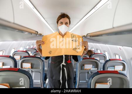 Stewardess demonstriert, wie man Rettungsweste im Flugzeug verwendet Stockfoto