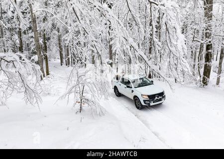 Geländewagen in verschneite Landschaft, schöne verschneite Gasse zu Beginn des Winters, verschneite Straße im Wald, Stockfoto