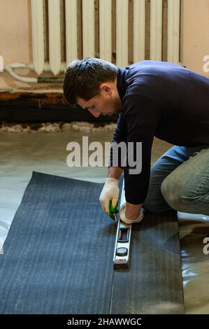 Die Bänder des Dachmaterials, schneidet der Meister die Dachmaterialien aus der Rolle, der Abdichtung des Bodenbelags, den Reparaturarbeiten. Stockfoto