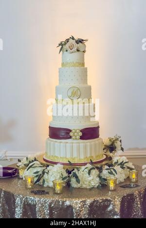 6-stufiger Hochzeitstorte mit eingraviertem Buchstaben m und gelber Spitze und rotem Band Stockfoto