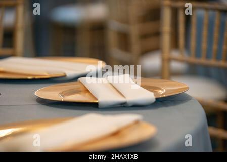Goldene Teller und beige Servietten als Tischdeket Stockfoto