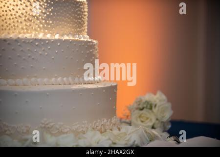 Nahaufnahme oder weißer dreistufiger Hochzeitstorte mit weißen Perlen und Blumen in aufrichtendem Stil Stockfoto