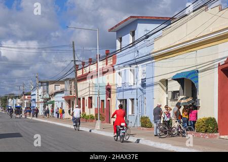 Kubaner stehen vor einem pastellfarbenen Laden in der Hauptstraße der Stadt Guáimaro im südlichen Teil der Provinz Camagüey, Kuba, Karibik Stockfoto