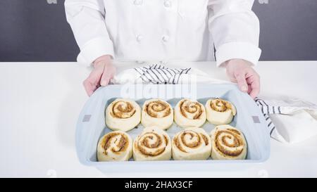 Ungebackene Zimtbrötchen in einer blauen Backform. Stockfoto