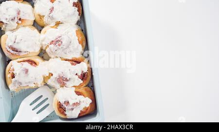 Flach liegend. Glasur frisch gebackene Zimtschnecken in einer blauen Backform. Stockfoto