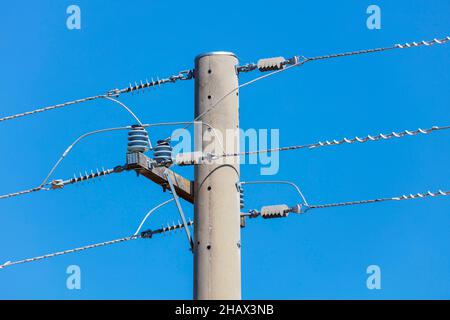 Foto eines Telefonpfostens aus Beton und Kabel vor blauem Himmel Stockfoto