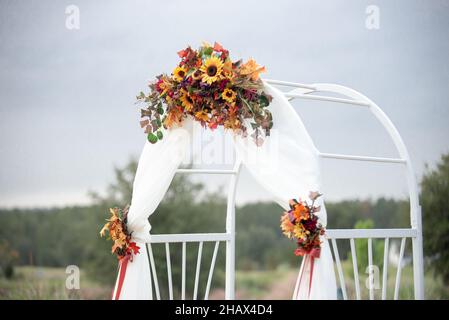 Weißer Hochzeits-Bogen in weißem Tuch und mit Sonnenblumen geschmückt Stockfoto