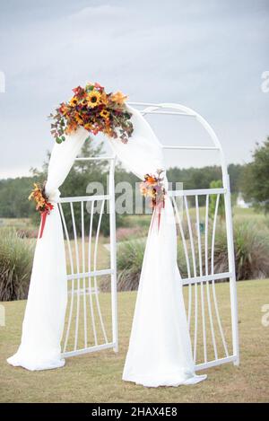 Weißer Hochzeits-Bogen in weißem Tuch und mit Sonnenblumen geschmückt Stockfoto