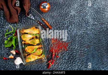 Hähnchenschenkel mit Rosmarin in einer Backform in Nahaufnahme auf dem Tisch. Stockfoto