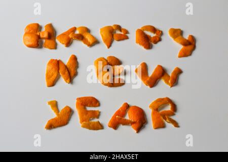 Unschärfe-Effekt Neujahrs-Wort, dargestellt durch orange trockene Schale auf grauem Hintergrund. Dekoration für Silvester, Konzept. Grußkarte. Text und DIY-Briefe. Stockfoto