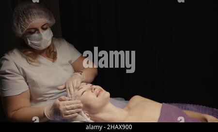 Junge hypnotische Gesichtsfrau erhält Anti-Aging-Gesichtsmassage im Spa-Salon Relax. Wellness Körper Hautpflege Gesicht Schönheitsbehandlung, Verjüngung procedu Stockfoto