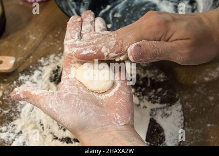 Weibliche Hände bereiten Teig zu, Formen Käsepfannkuchen, verschmutzt in Mehl, Draufsicht. Stockfoto