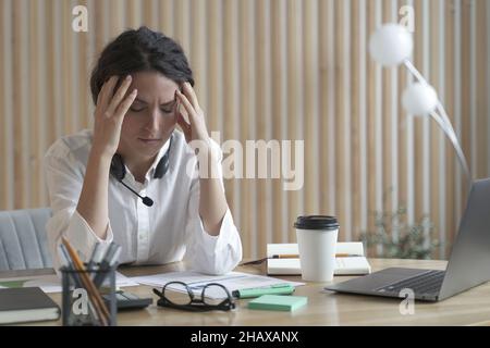Müde spanische Geschäftsfrau mit geschlossenen Augen sitzt am Arbeitsplatz im Büro und leidet unter Kopfschmerzen Stockfoto