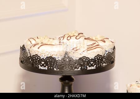 Verzierter Cupcake-Turm aus schwarzem Eisen mit Vanillekuchen, die mit Schokoladenfuss beträufeln Stockfoto