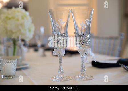 Zwei verzierte Kristallgläser mit weißen Schleifen auf dem Tisch Stockfoto