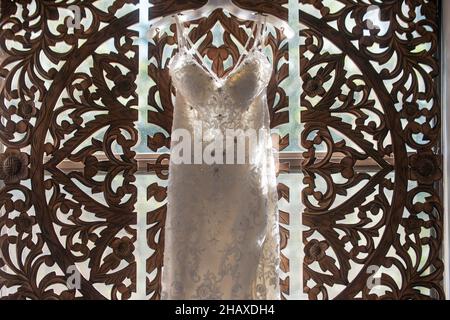 Wunderschöne weiße Bräute Kleid hängen von verzierten Fenster Stockfoto
