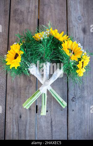 Wunderschöne Sonnenblumen- und rote Rosen-Brautsträuße auf Holzvertäfelung Stockfoto