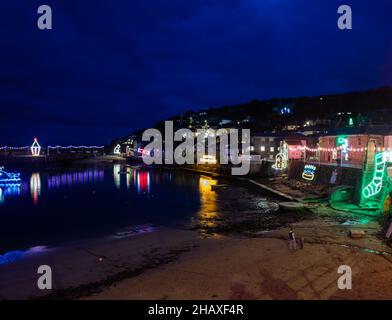 Mousehole,Cornwall,15th. Dezember 2021,Besucher besuchen Mousehole, um die berühmten Weihnachtslichter in Cornwall zu sehen. Bei Flut glitzern die Lichtreflexe über den Hafen. Es gibt alle traditionellen festlichen Lichter einschließlich einer Katze und einer Maus.Quelle: Keith Larby/Alamy Live News Stockfoto