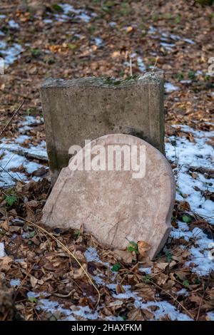 Alte alte alte verlassene jüdische Friedhof im Wald im Winter. Gealterte Grabsteine oder Grabsteine auf dem Friedhof. Stockfoto