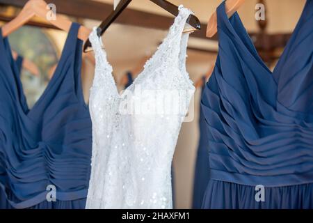 Wunderschöne weiße Bräute Kleid hängen von Bettgestell mit blauen Brautjungfern Kleider Stockfoto