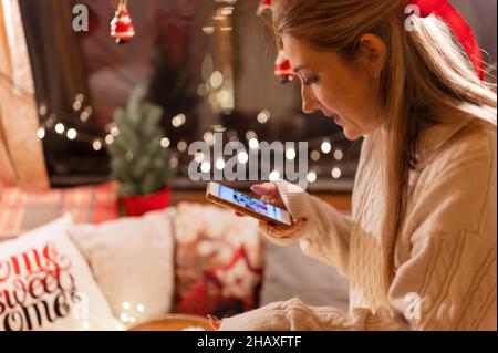 Offen junge Frau in den Händen halten Smartphone und suchen oder Anzeigen von Fotos auf dem Display. Genuss entspannen im Camping-Haus in gemütlichem Bett auf glücklichen chris Stockfoto