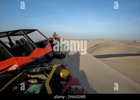 Sanddünen in der Wüstenoase von Huacachina machen Touristen Fotos und fahren mit dem Dune Buggy Sandboard mit Führern, bevor sie die Nacht verbringen. Stockfoto